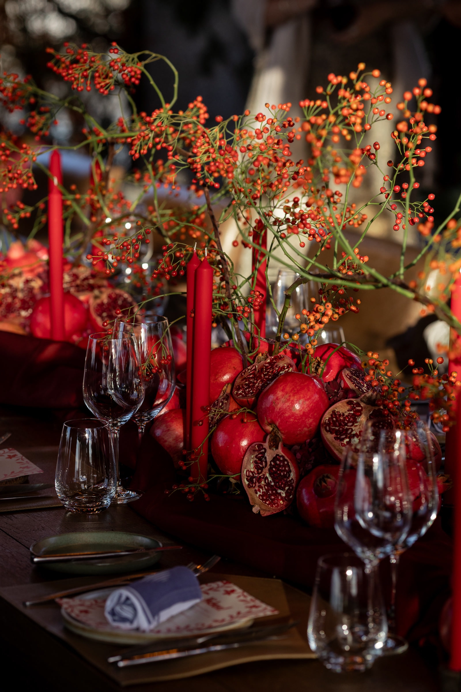 Herbstliche Tischdekoration mit Granatäpfeln, Beeren und roten Kerzen