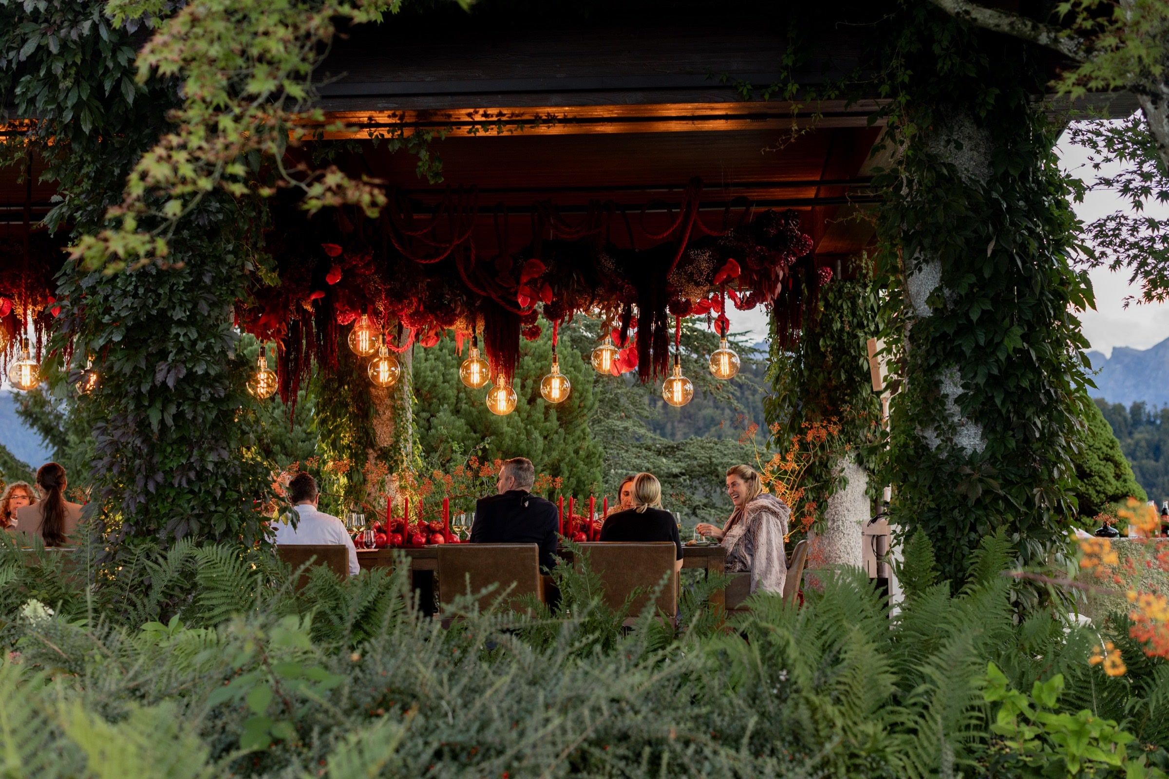 Outdoor-Dinner unter einem mit Blumen und Lichterketten geschmückten Pavillon